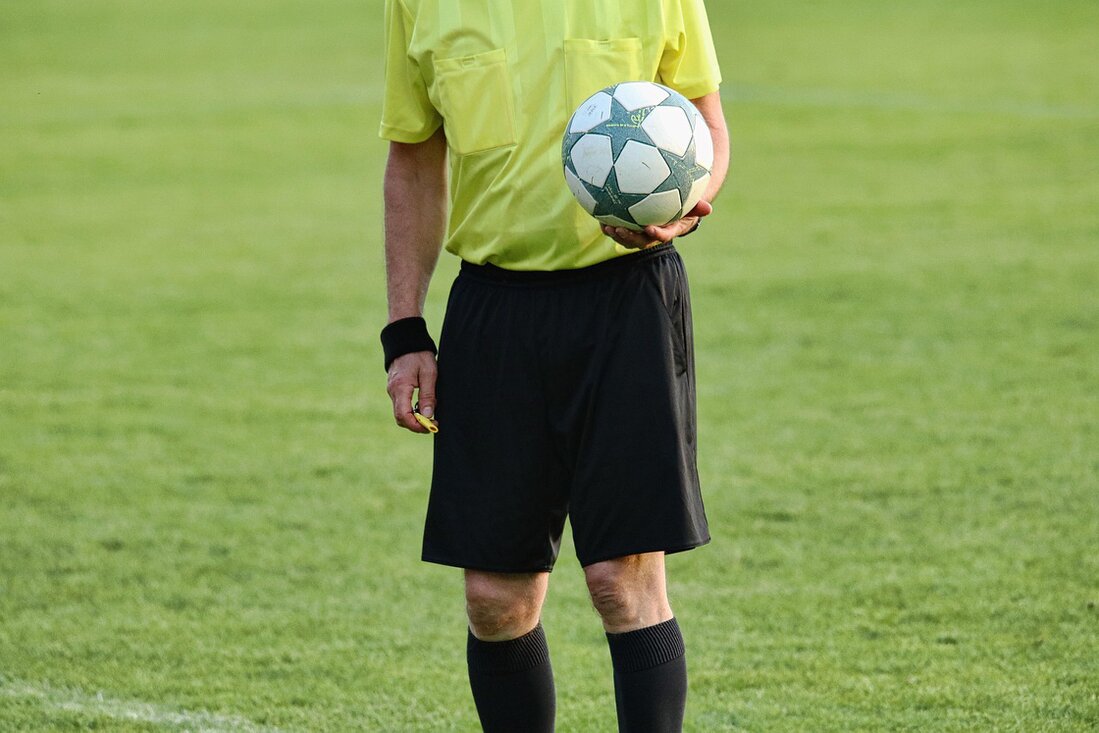Schiedsrichter mit Trillerpfeife auf dem Fußballplatz.